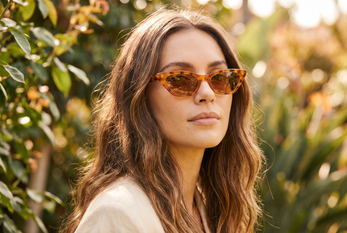 A woman wearing amber tortoiseshell cat-eye sunglasses in warm afternoon light