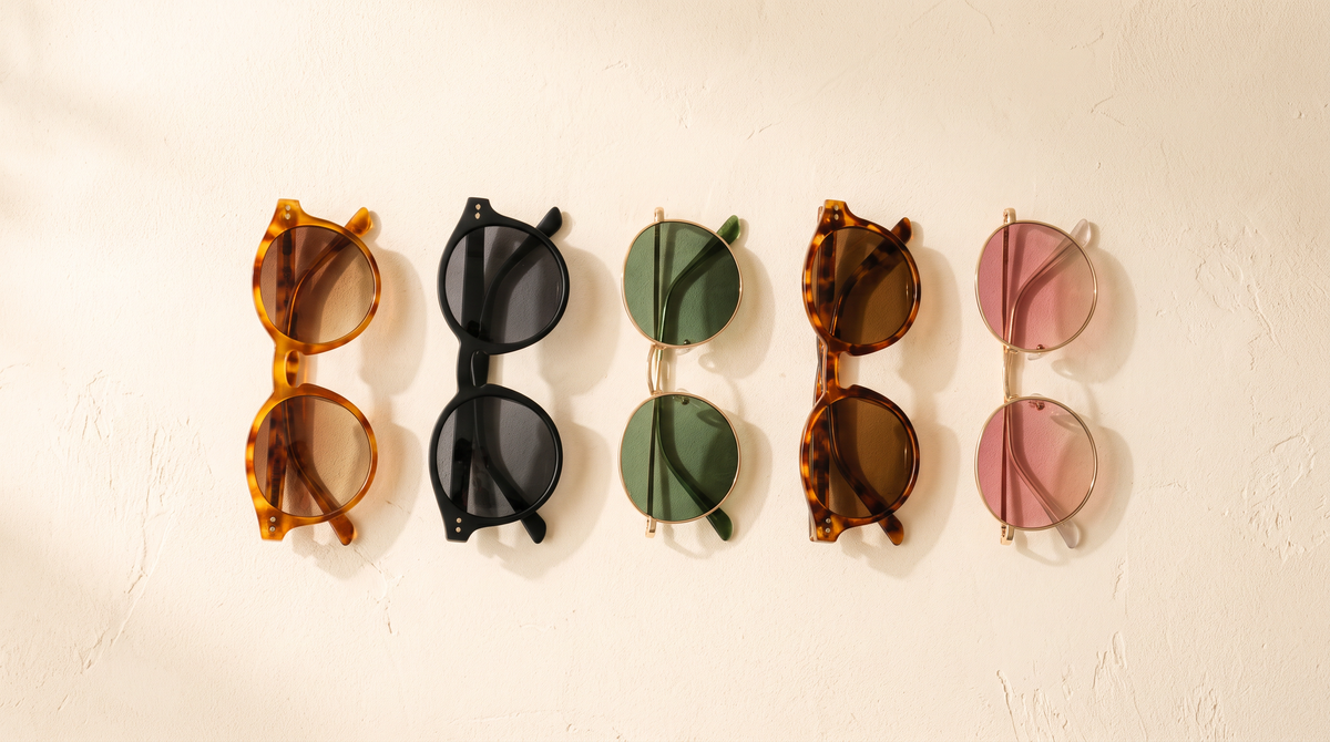 Five pairs of round sunglasses arranged on a cream surface