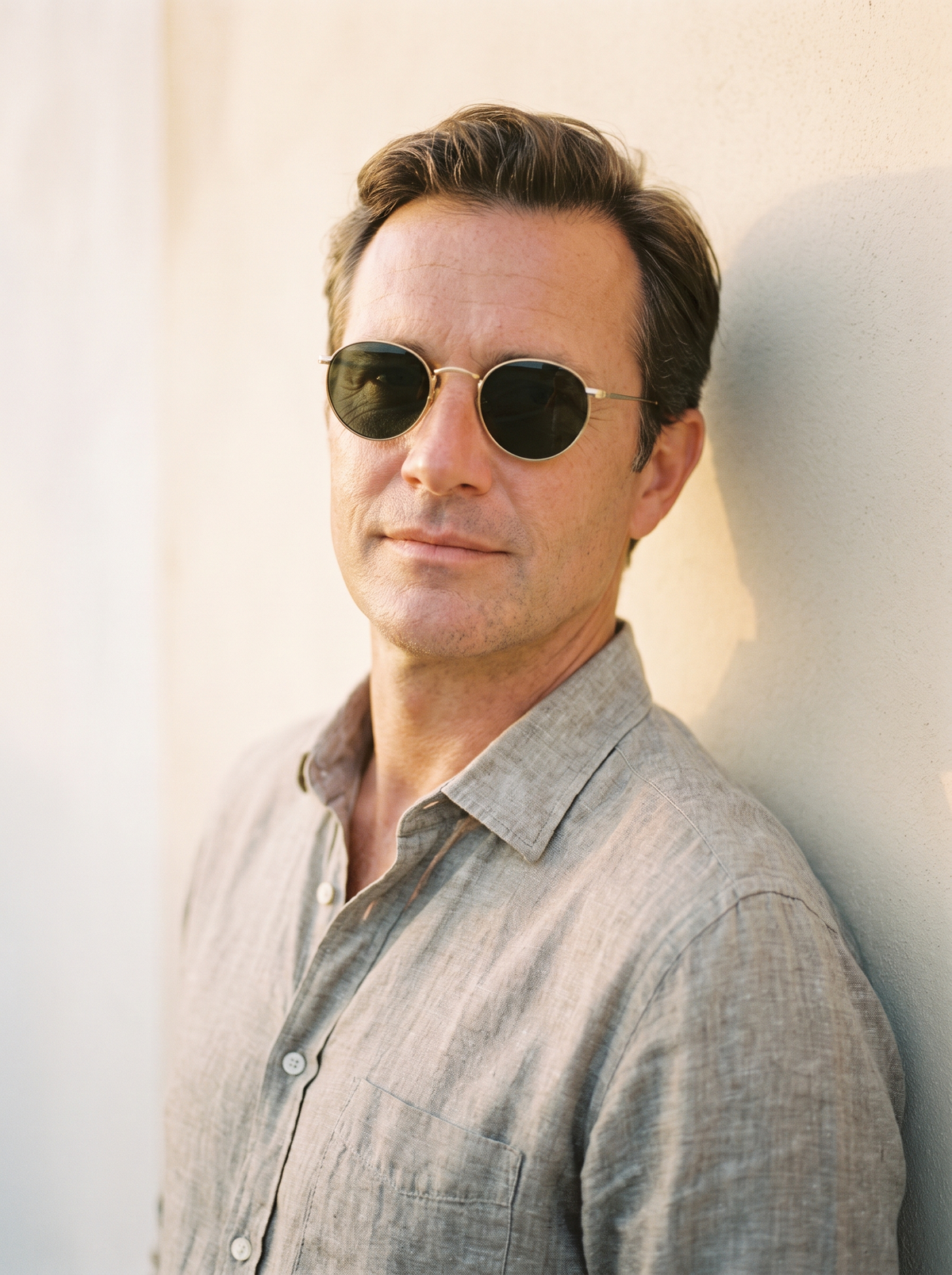 Man wearing round gold-frame sunglasses in warm light