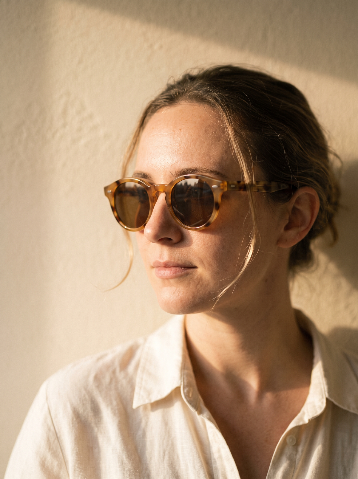 Woman wearing round tortoiseshell sunglasses in golden light